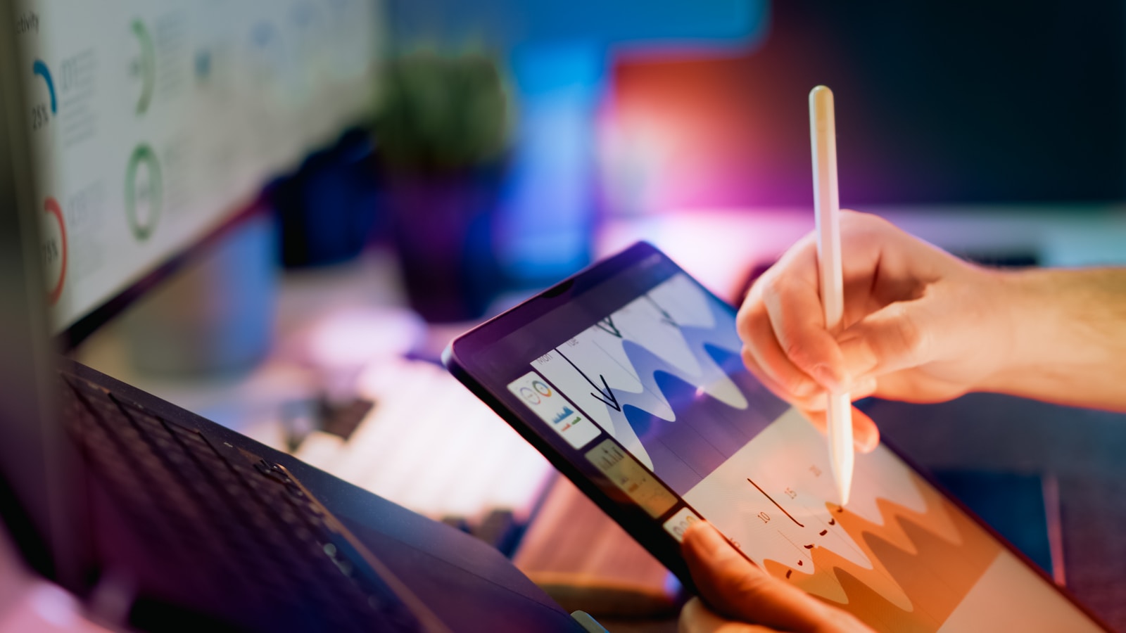 A person using a stylus on a tablet displaying colored charts